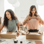 Women co-founders preparing labeled boxes for shipping, showcasing their business's GS1 certification for retail standards.