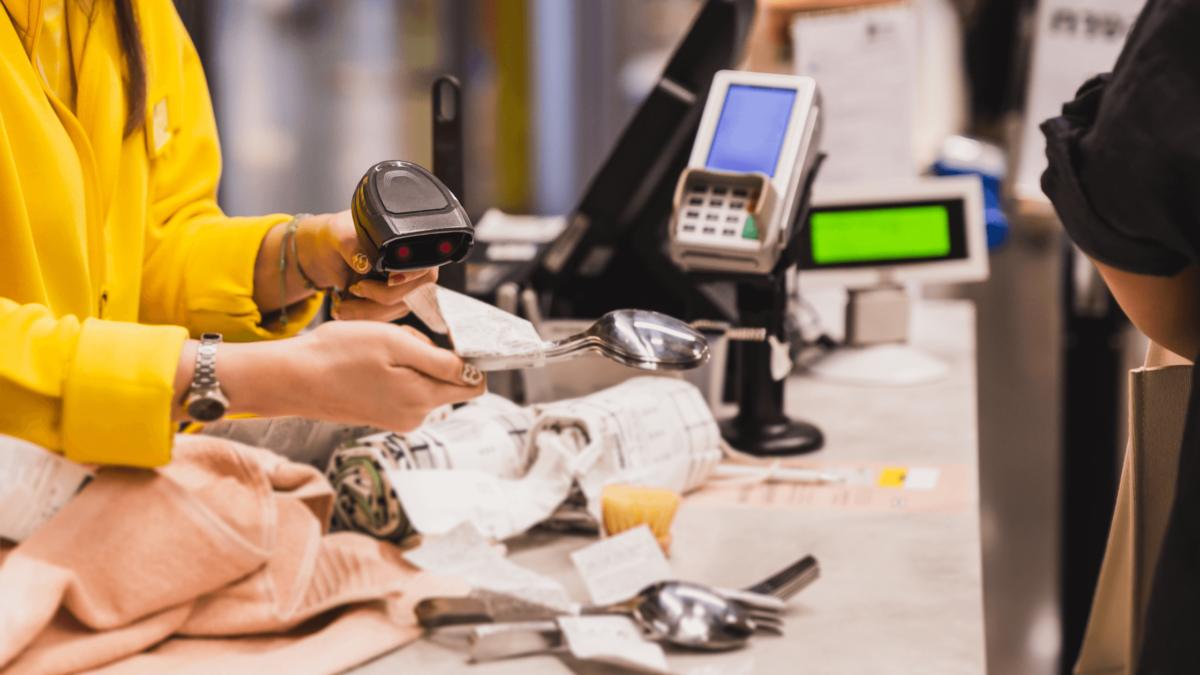 Retail worker scanning receipts at a checkout counter, symbolizing inventory management and product tracking.