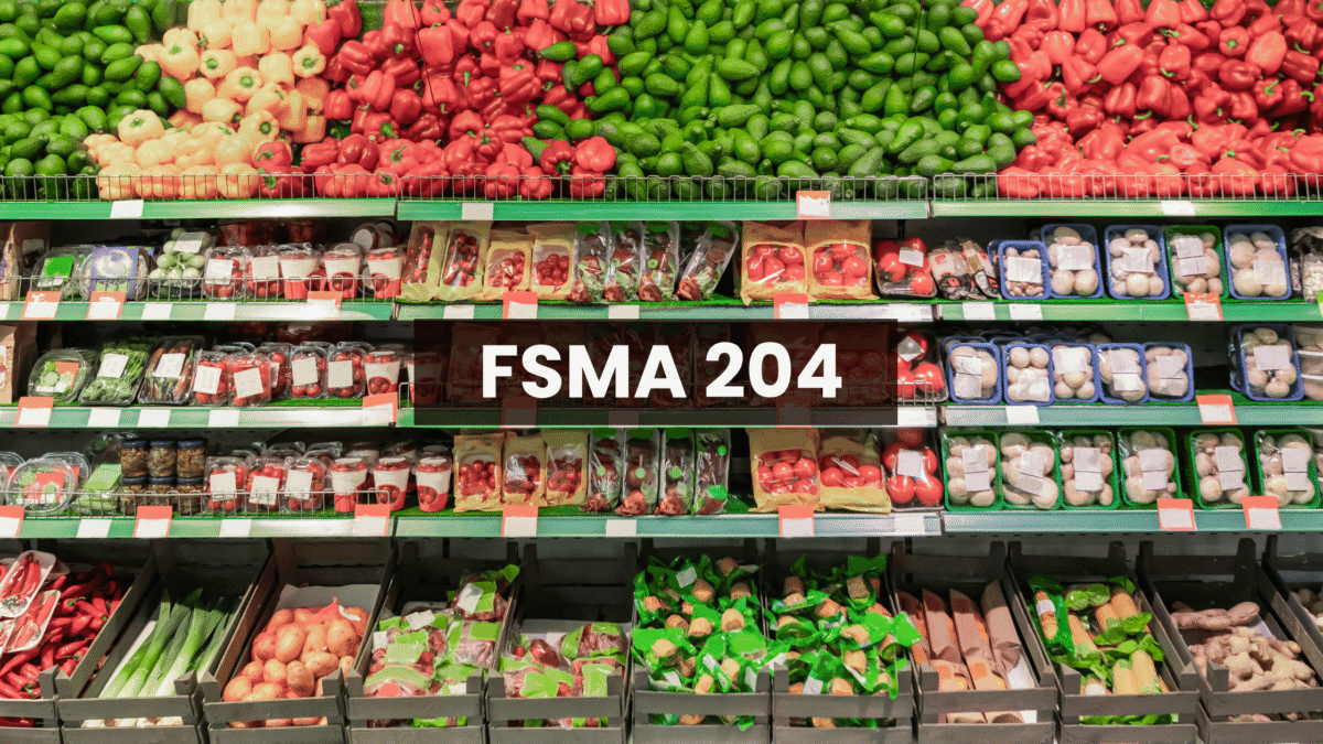 A produce aisle in a grocery store, with shelves stocked with various fruits and vegetables like peppers, tomatoes, avocados, mushrooms, onions, and leafy greens, with a title at the center that reads "FSMA 204."